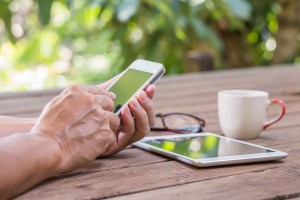 Man hands touching smart phone with green tree background